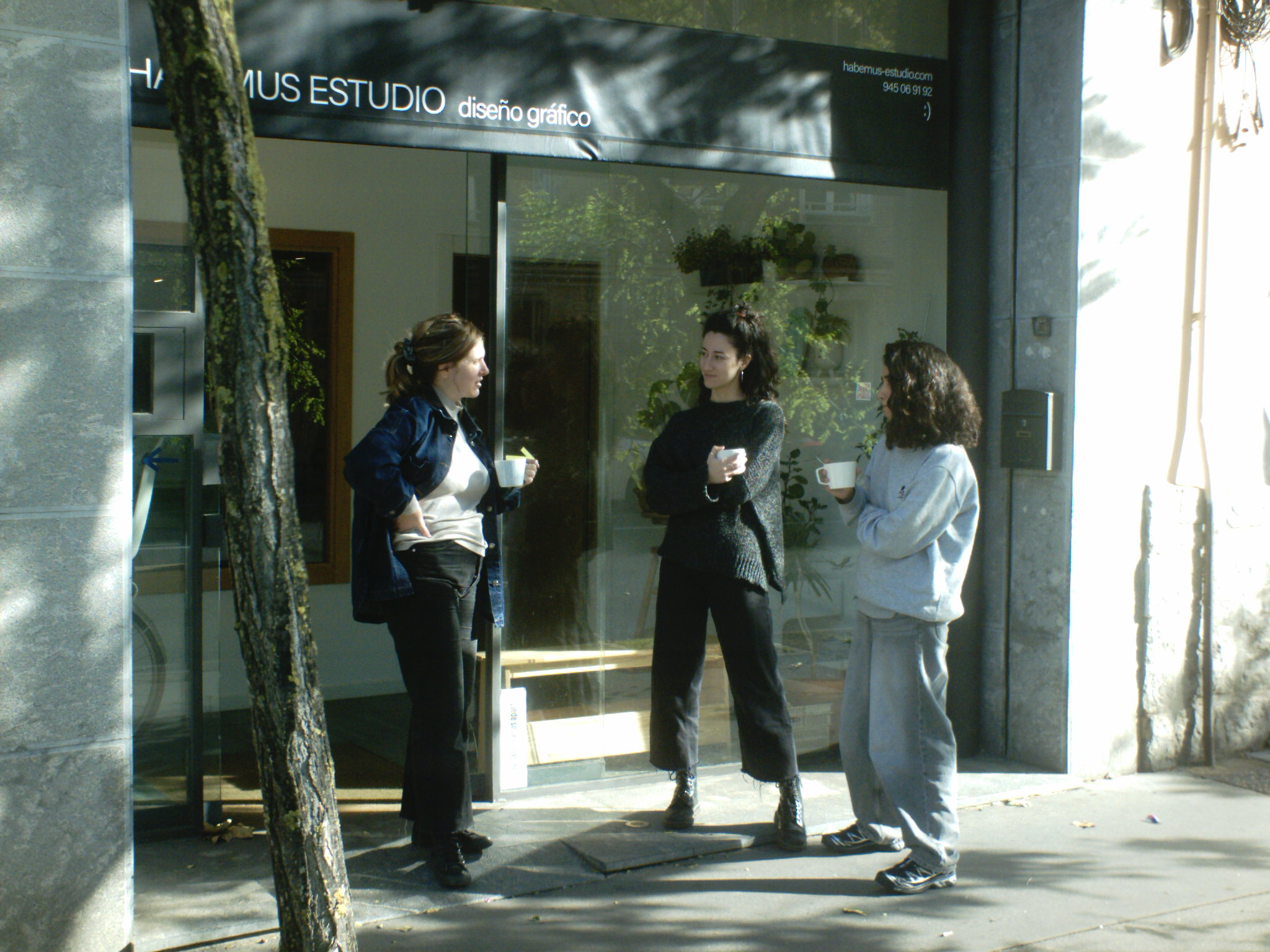 Laura, Ane y Maria en el exterior del estudio, de pie, tomando un cafe.