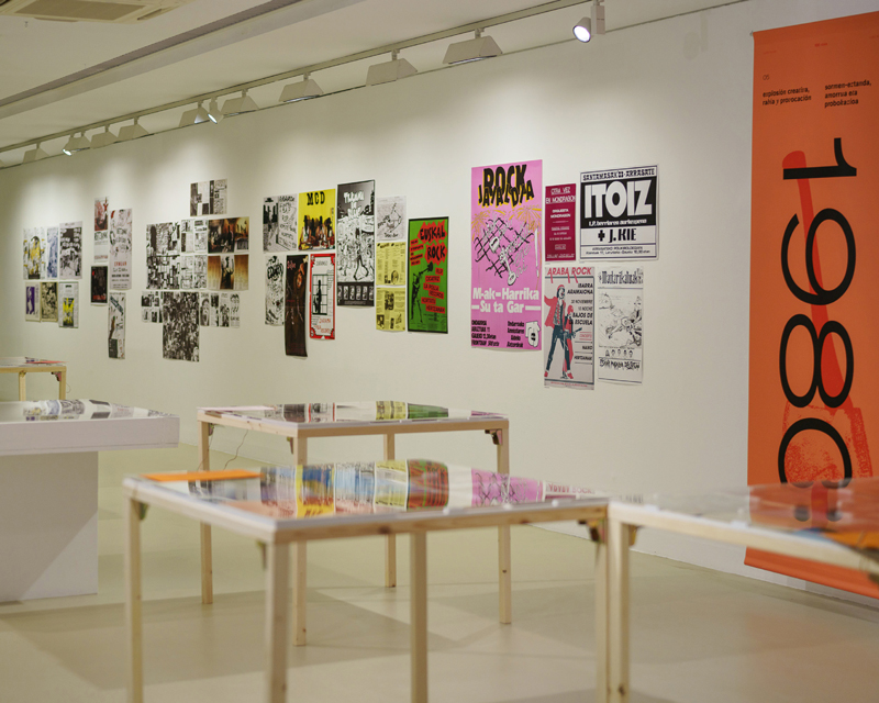 Vista general de sala de exposicion, con una lona naranja con el texto 1980